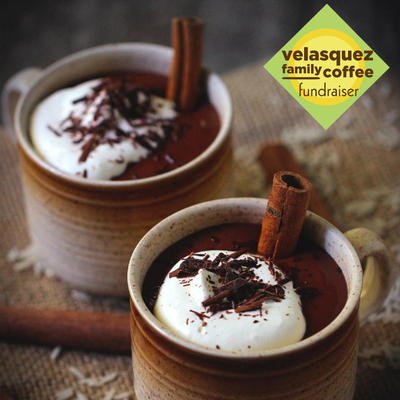 Mugs of hot cocoa topped with whipped cream, chocolate sprinkles with a cinnamon stick