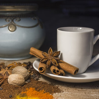 Images shows a coffee cup, cinnamon sticks and other spices. This flavor celebrates the fall flavors of nutmeg, cinnamon and spice