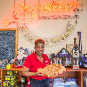 Loretta in New Orleans holding plate of sweet caramelized pralines surrounded by holiday decorations and gifts